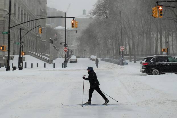 A person on skis walks amid a major winter storm spreading across a large swath of the United States, in Brooklyn