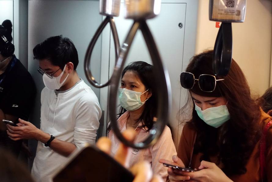 People wear masks as they commute to work, after the particulate matter (PM) reached hazardous levels in Bangkok