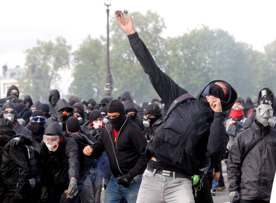 Tear gas floats around masked protesters during clashes with French CRS riot police at the May Day labour union rally in Paris