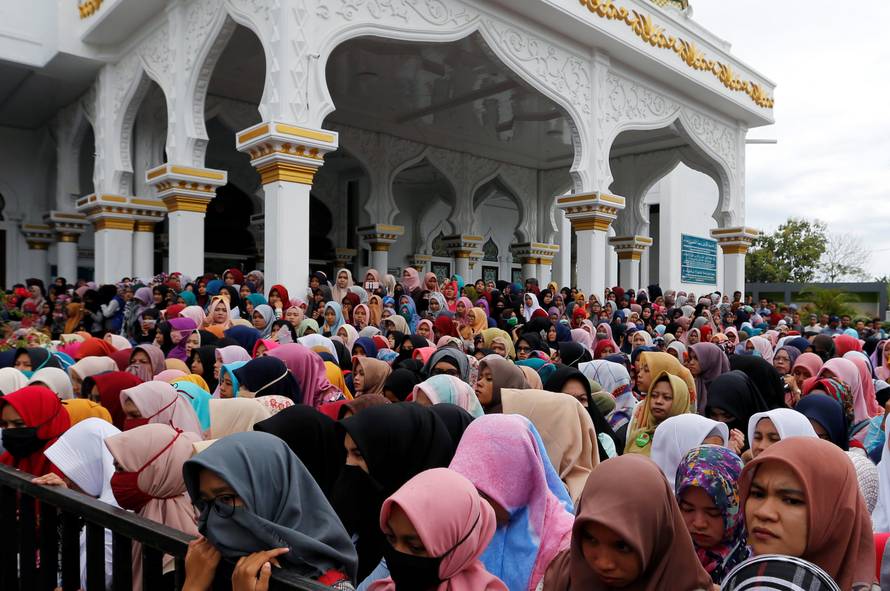 Indonesian women stand in front of the Syuhada mosque as they watch a man being publicly caned for having gay sex, in Banda Aceh
