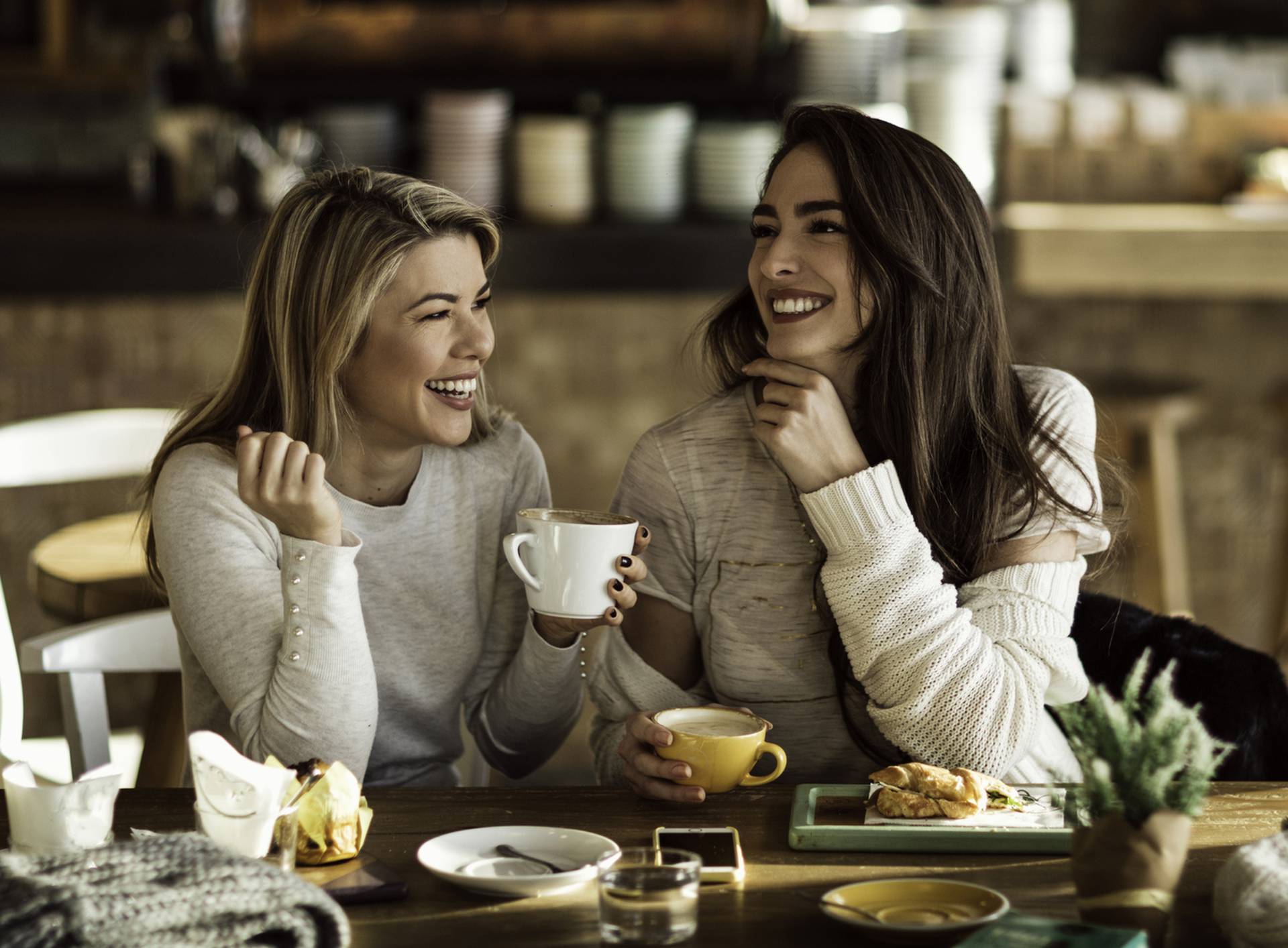 Two cheerful women having fun during coffee time in a cafe.