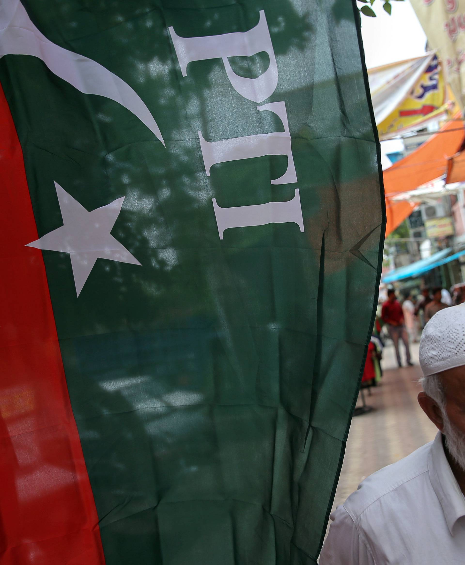 A man walks past a flag of the Pakistan Tehreek-e-Insaf (PTI) at a market, a day after general election in Islamabad