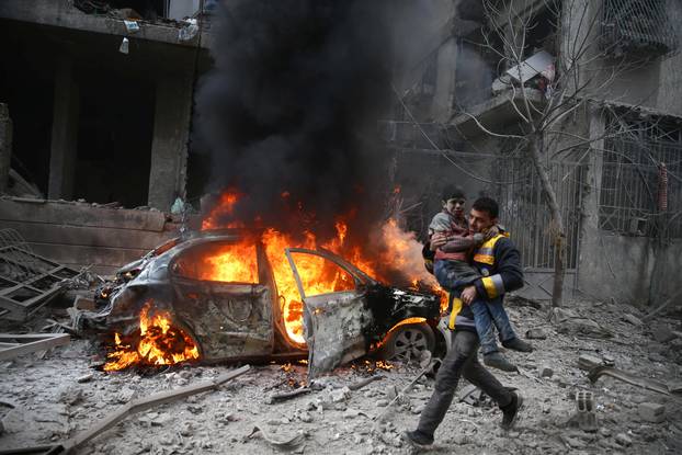 Syria Civil Defence member carries a wounded child in Hamoria, Eastern Ghouta, Damascus