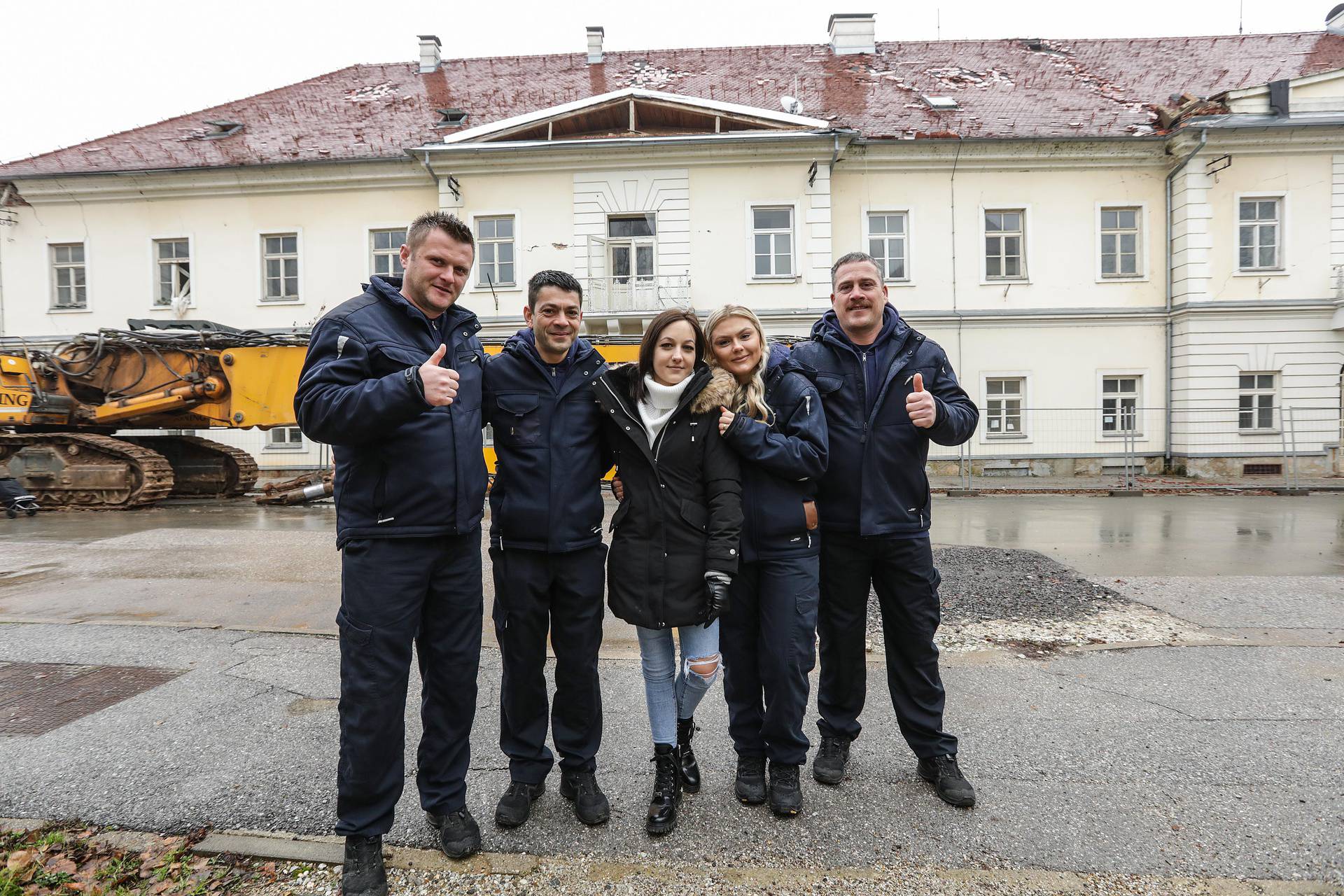 Vatrogasci s mladom djevojkom koju su izvukli iz ruševina nakon potresa koji je zadesio Petrinju prošle godine