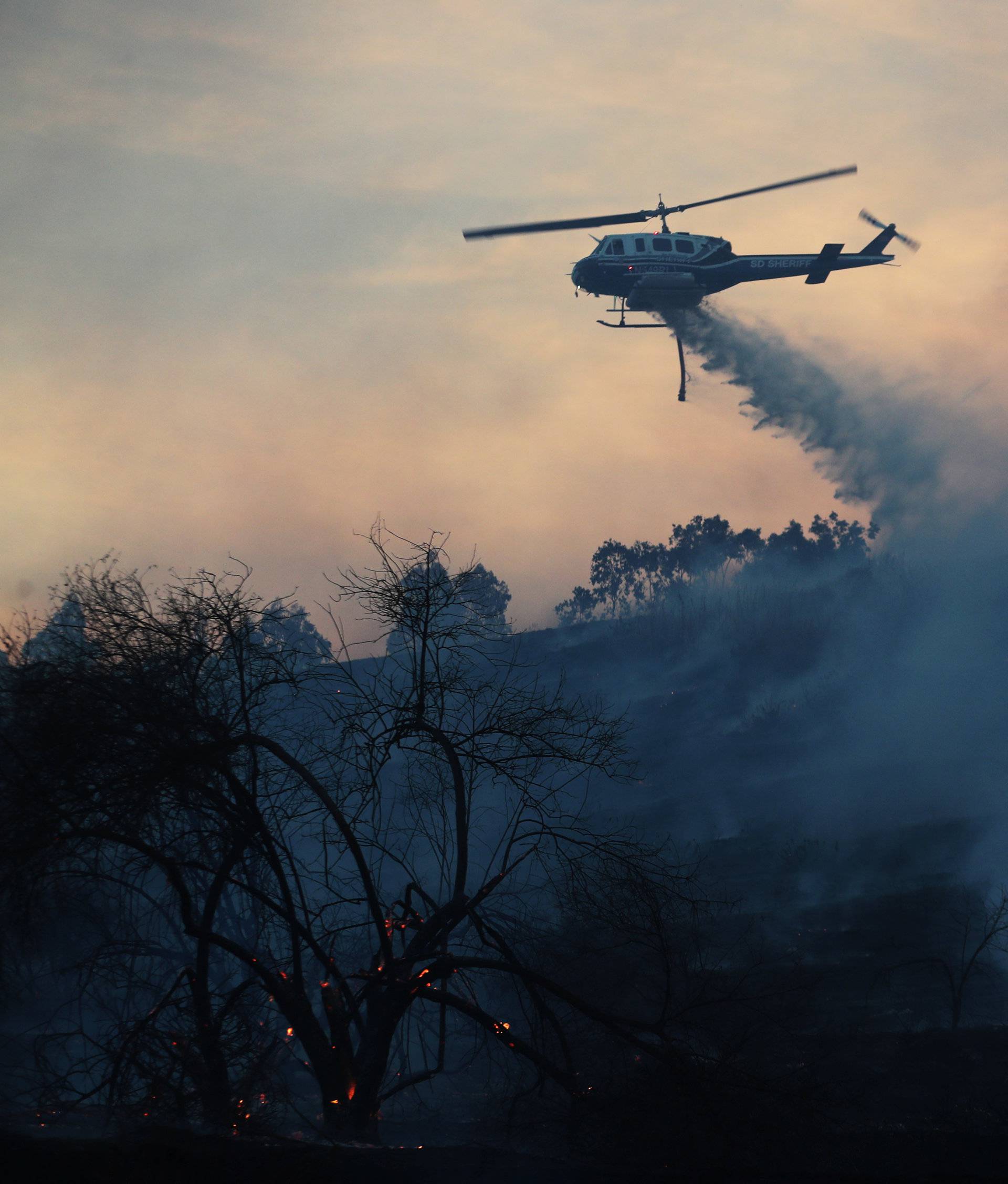 A firefighting helicopter makes a water drop on the Lilac Fire a fast moving wildfire in Bonsall