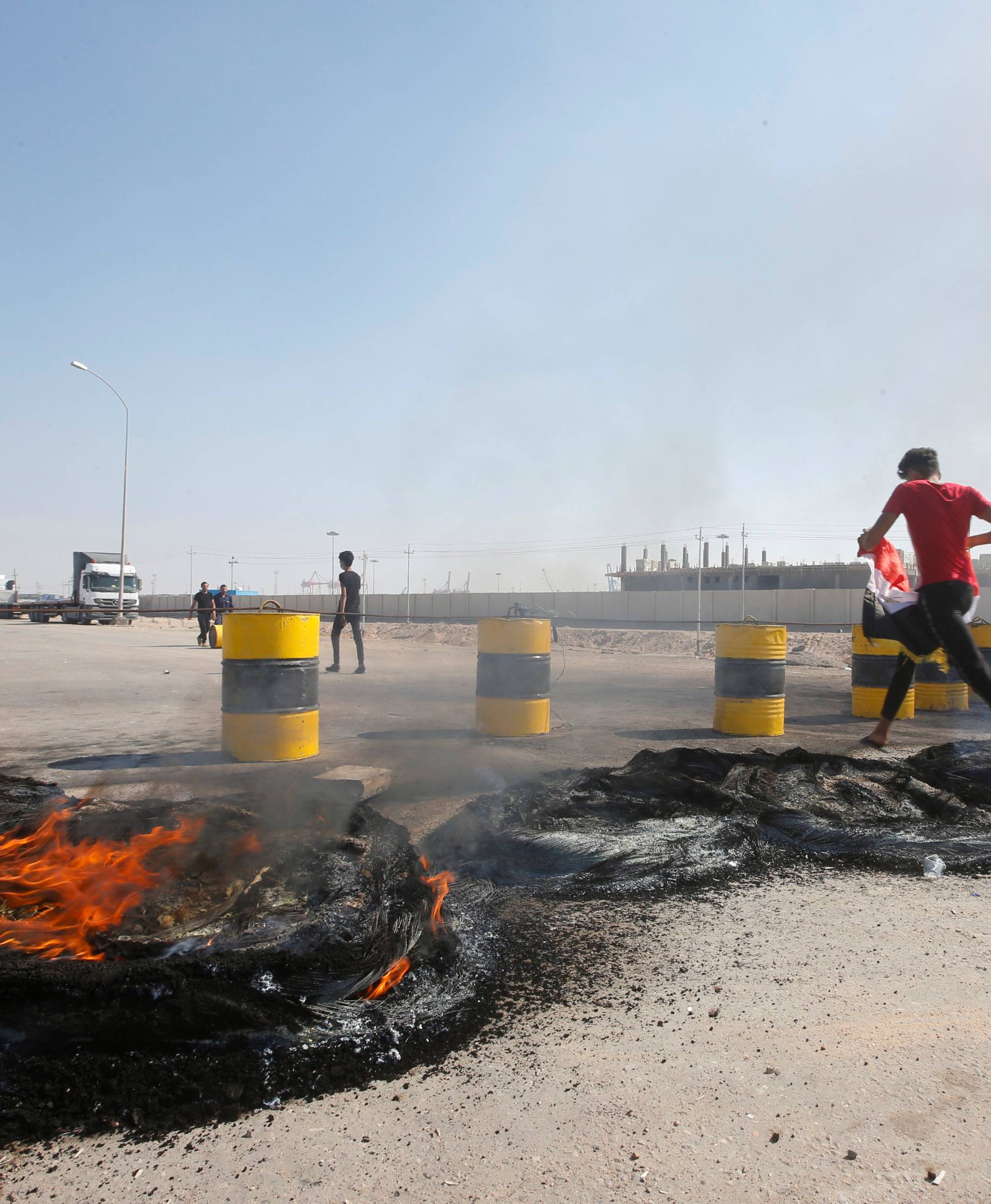 Iraqi protesters burn tires as they block the entrance of Umm Qasr Port south of Basra
