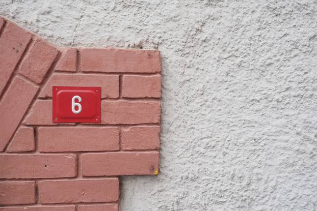 House number six displayed on a textured wall surface