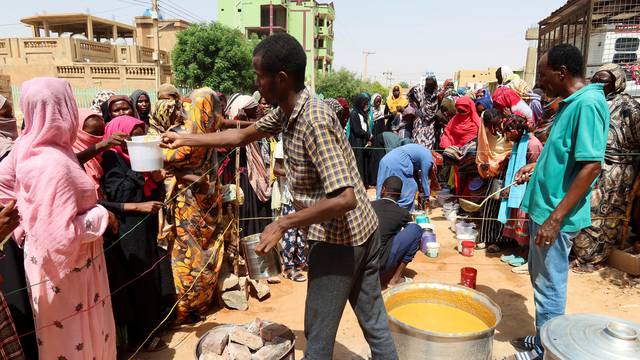 Volunteer distributes food to people in Omdurman