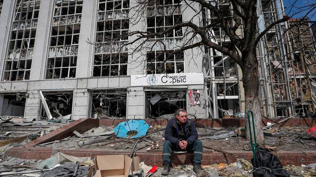 A resident looks on near a building destroyed in the course of the Ukraine-Russia conflict, in Mariupol