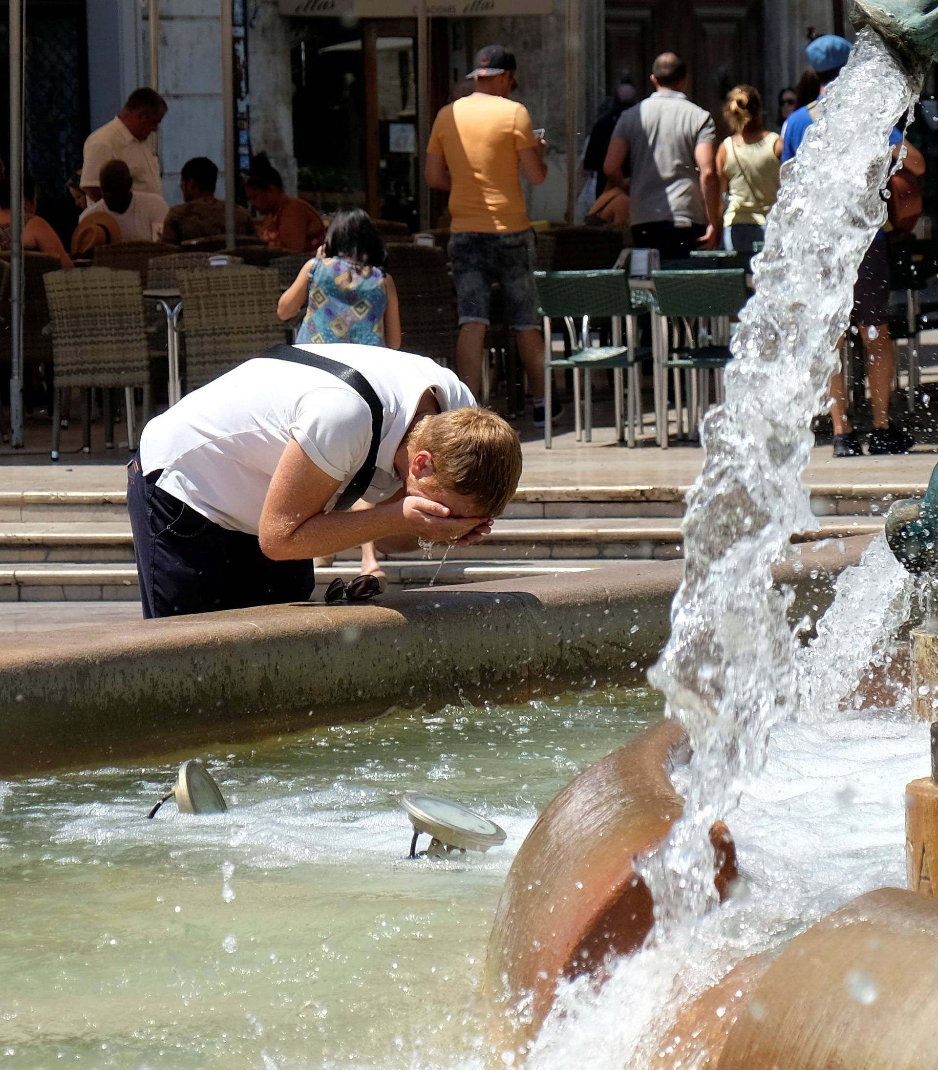 Tourists cool off at a fountain during the heatwave at the Virgin Square in Valencia