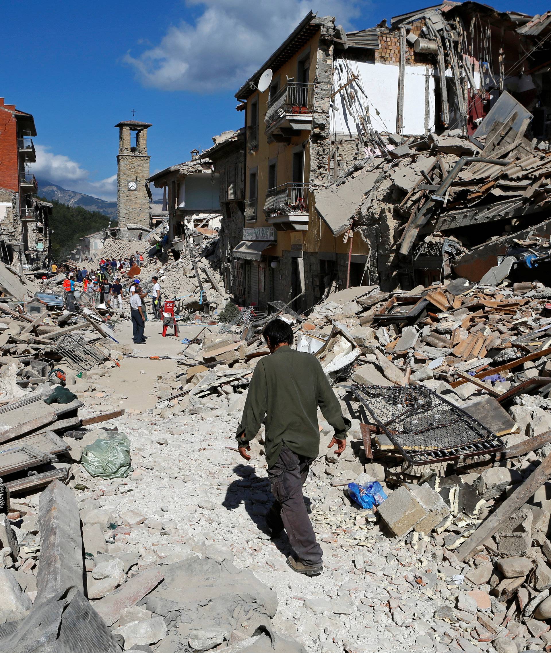 A man walks amidst rubble following an earthquake in Pescara del Tronto