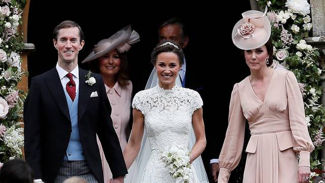 Pippa Middleton and James Matthews smile as they are joined by Britain's Catherine, Duchess of Cambridge after their wedding at St Mark's Church in Englefield