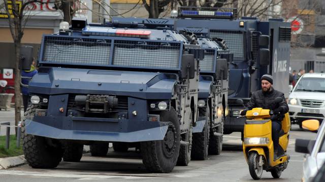 A man rides on a scooter along a street past parked Kosovo police armoured vehicles in southern part of Mitrovica