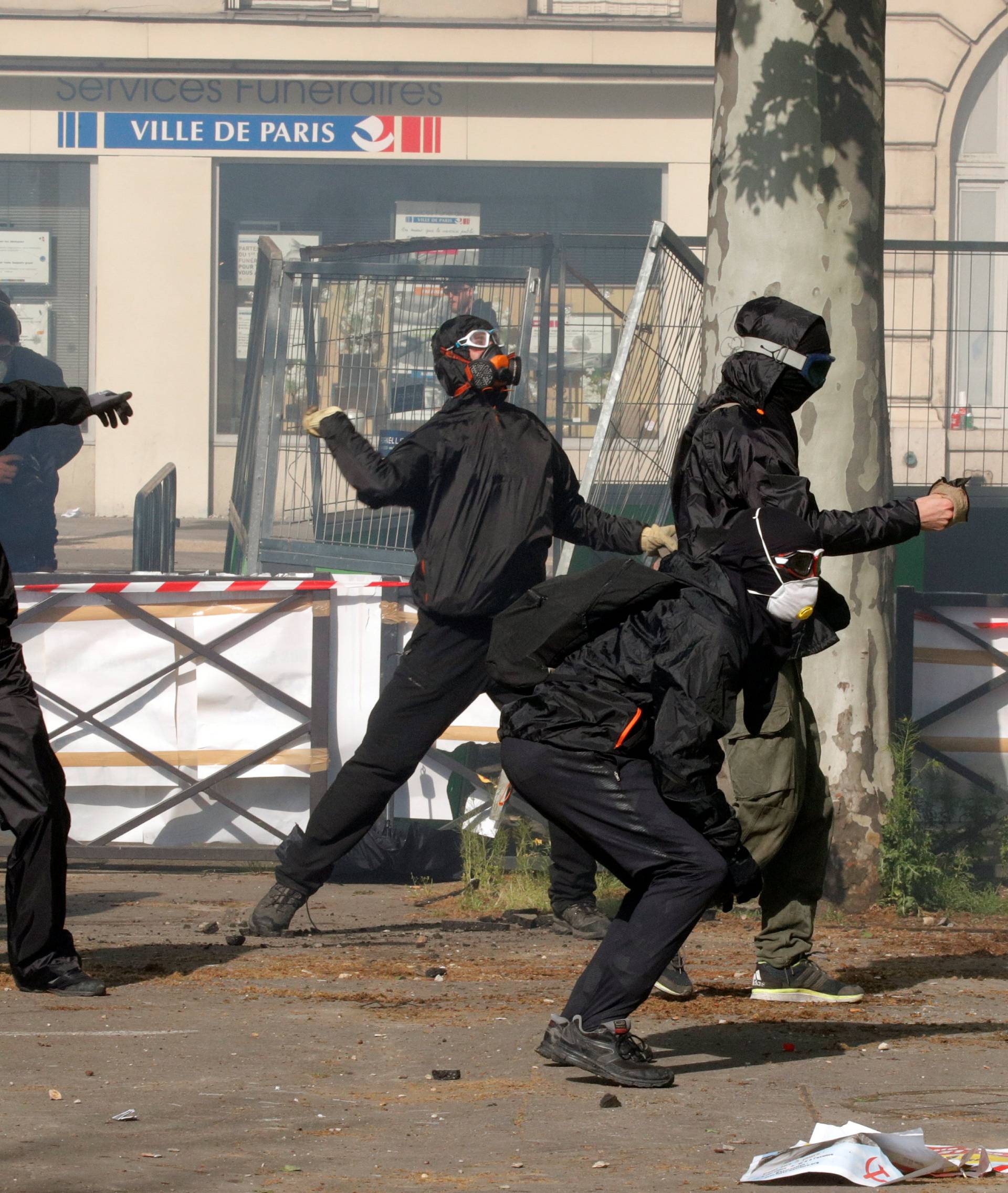 Tear gas floats around masked protesters during clashes with French CRS riot police at the May Day labour union rally in Paris