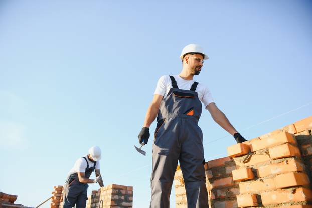 Man bricklayer installing bricks on construction site
