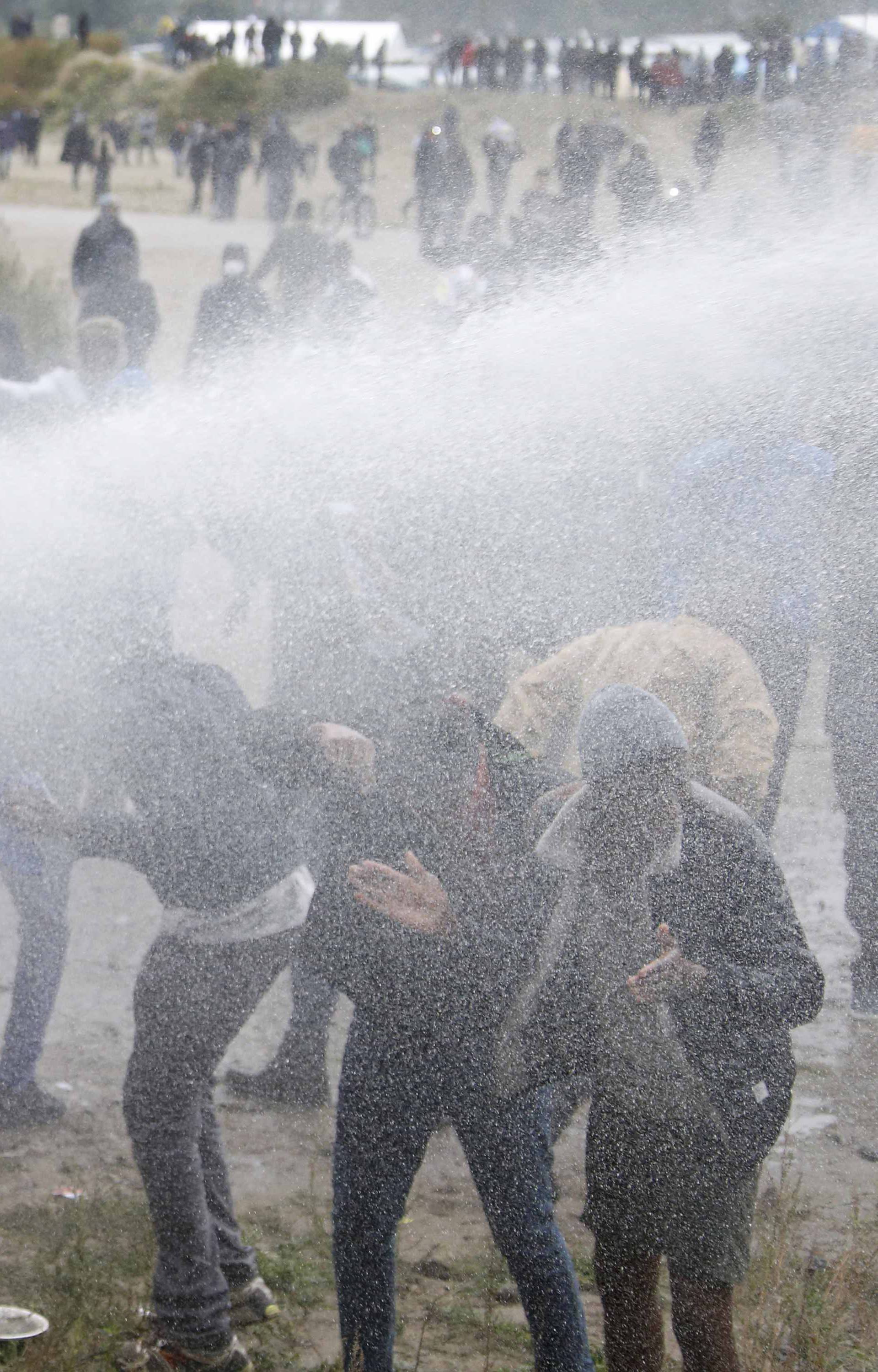 French police use water canon to disperse demonstrators who hold a march near the area called the "jungle" where migrants live in Calais