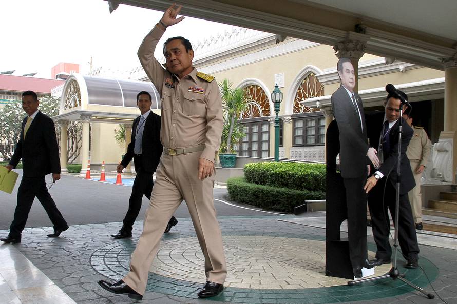 Thailand's Prime Minster Prayuth Chan-ocha waves to reporters next to a cardboard cut-out of himself at the government house in Bangkok