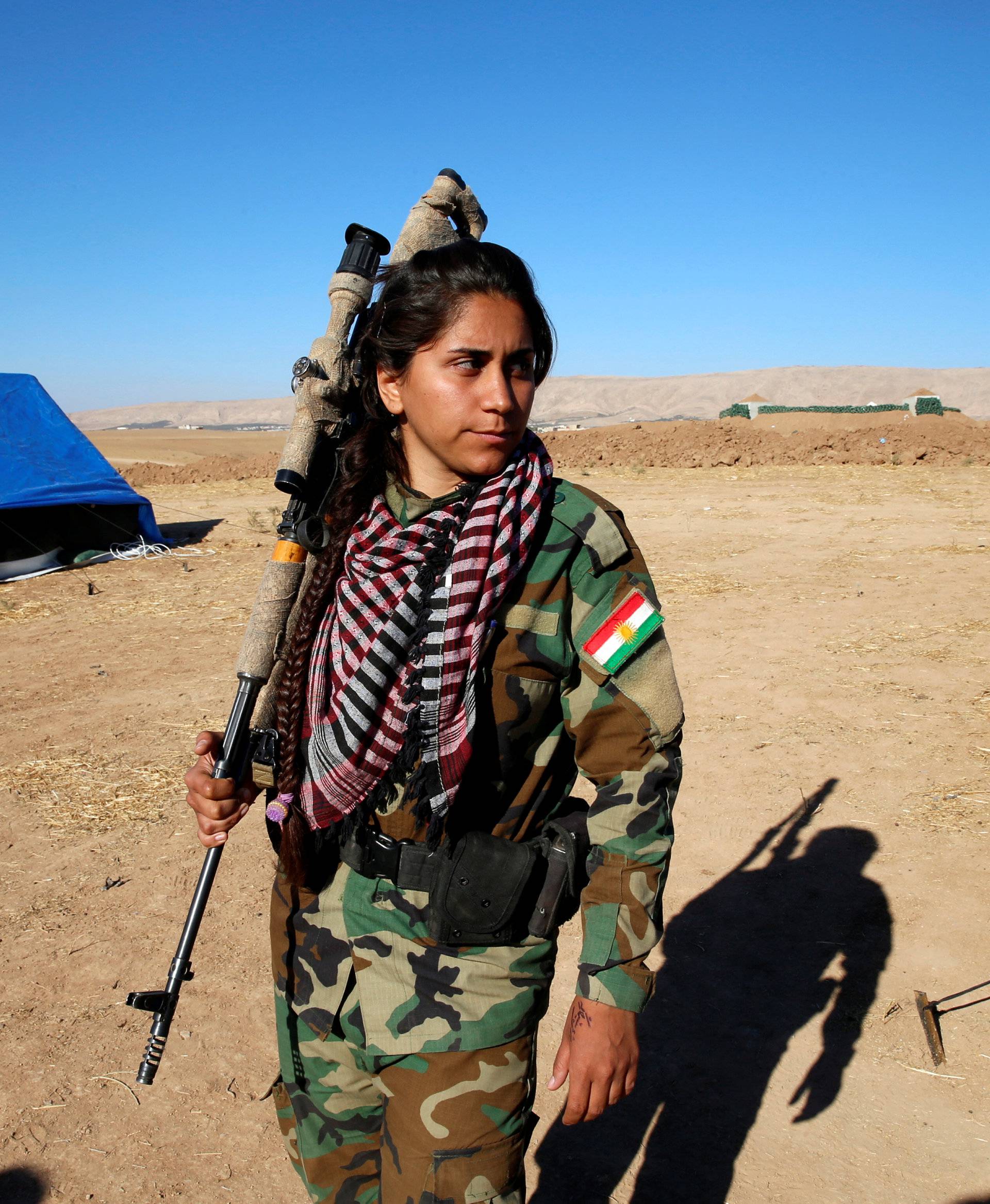 An Iranian-Kurdish female fighter carries her weapon during a battle with Islamic State militants in Bashiqa, near Mosul