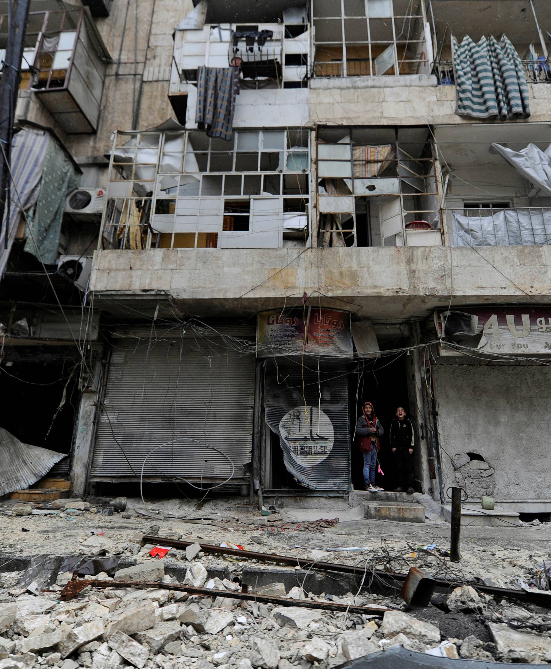 Boys stand amid the damage in the governemnt-held al-Shaar neighborhood of Aleppo