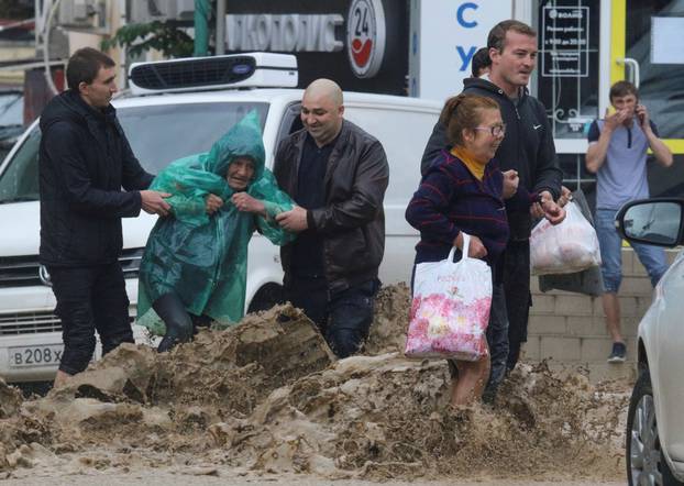 People cross a flooded street following heavy rainfall in Yalta