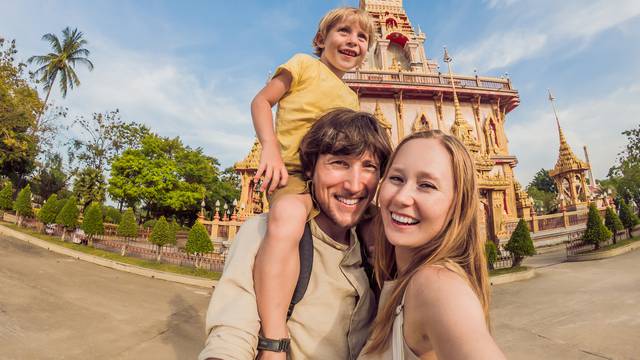 A happy family of tourists on the background of Wat Chalong in Thailand. Traveling with children concept