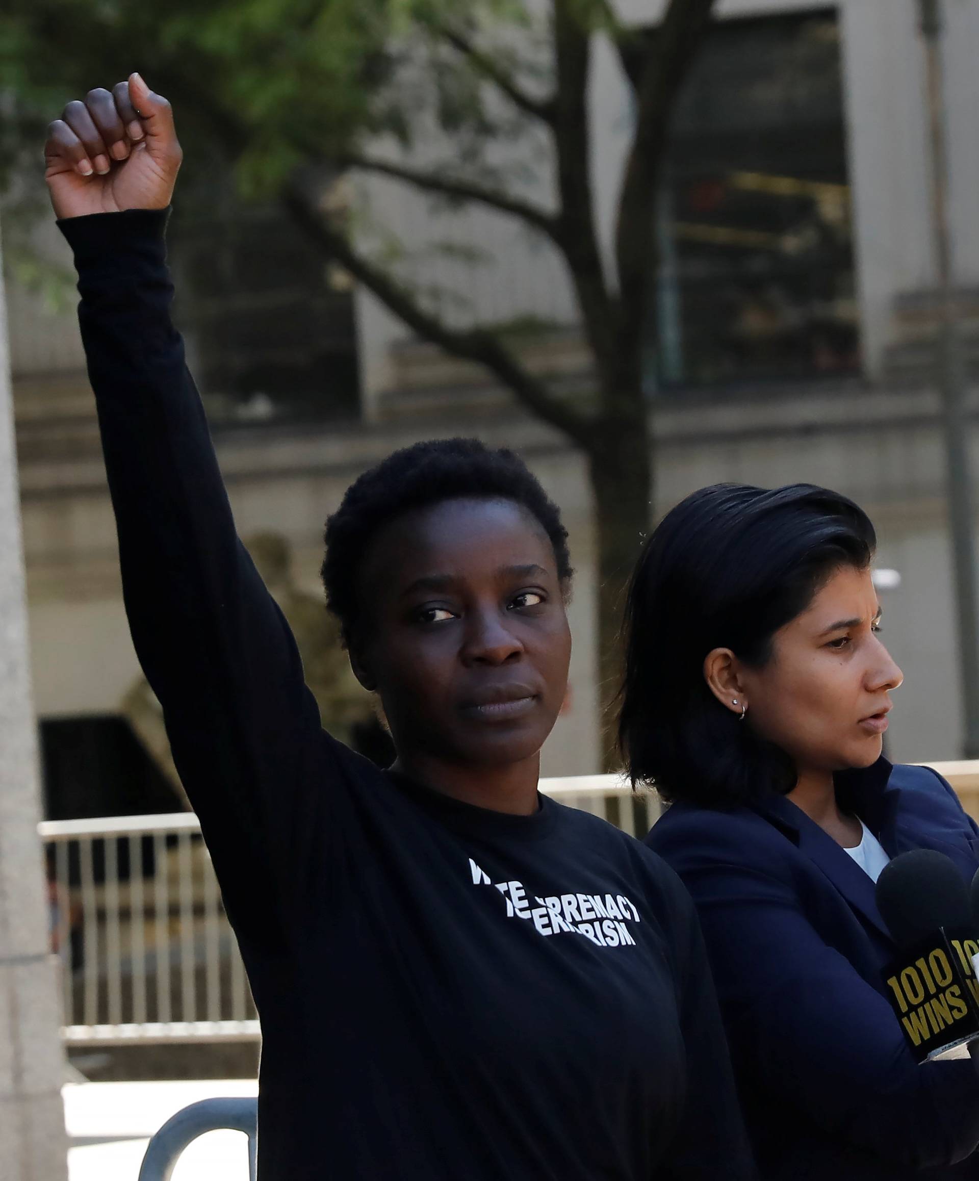 Patricia Okoumou raises her hand in the air after leaving federal court from her arraignment, a day after authorities say she scaled the stone pedestal of the Statue of Liberty to protest U.S. immigration policy, and speaking to the media in Manhattan