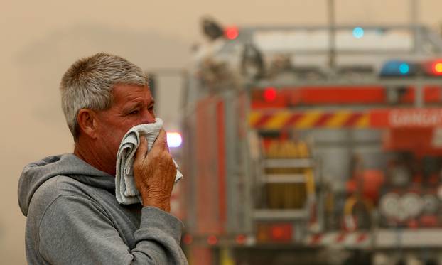 A resident watches the progress of bushfires near houses in Old Bar, New South Wales