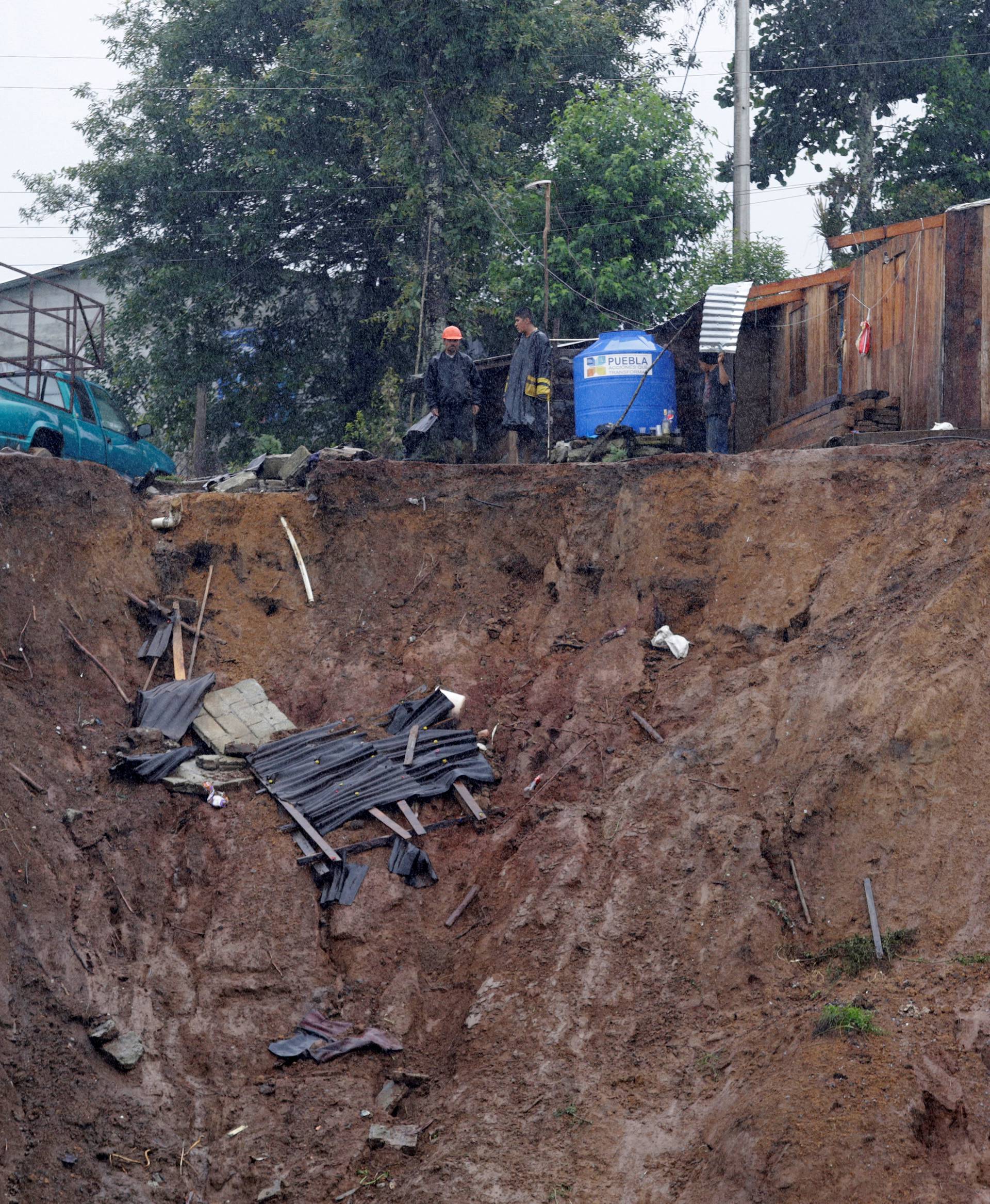 Residents stand outside their damaged houses after a mudslide following heavy showers caused by the passing of Tropical Storm Earl, in the town of Huauchinango