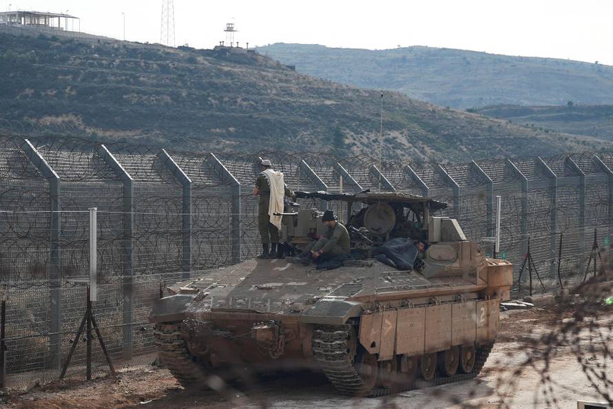Israeli soldiers on a Namer Armoured Personnel Carrier (APC) while one of them conducts morning prayers, along the Golan Heights side of the ceasefire line between Syria and the Israeli-occupied Golan Heights