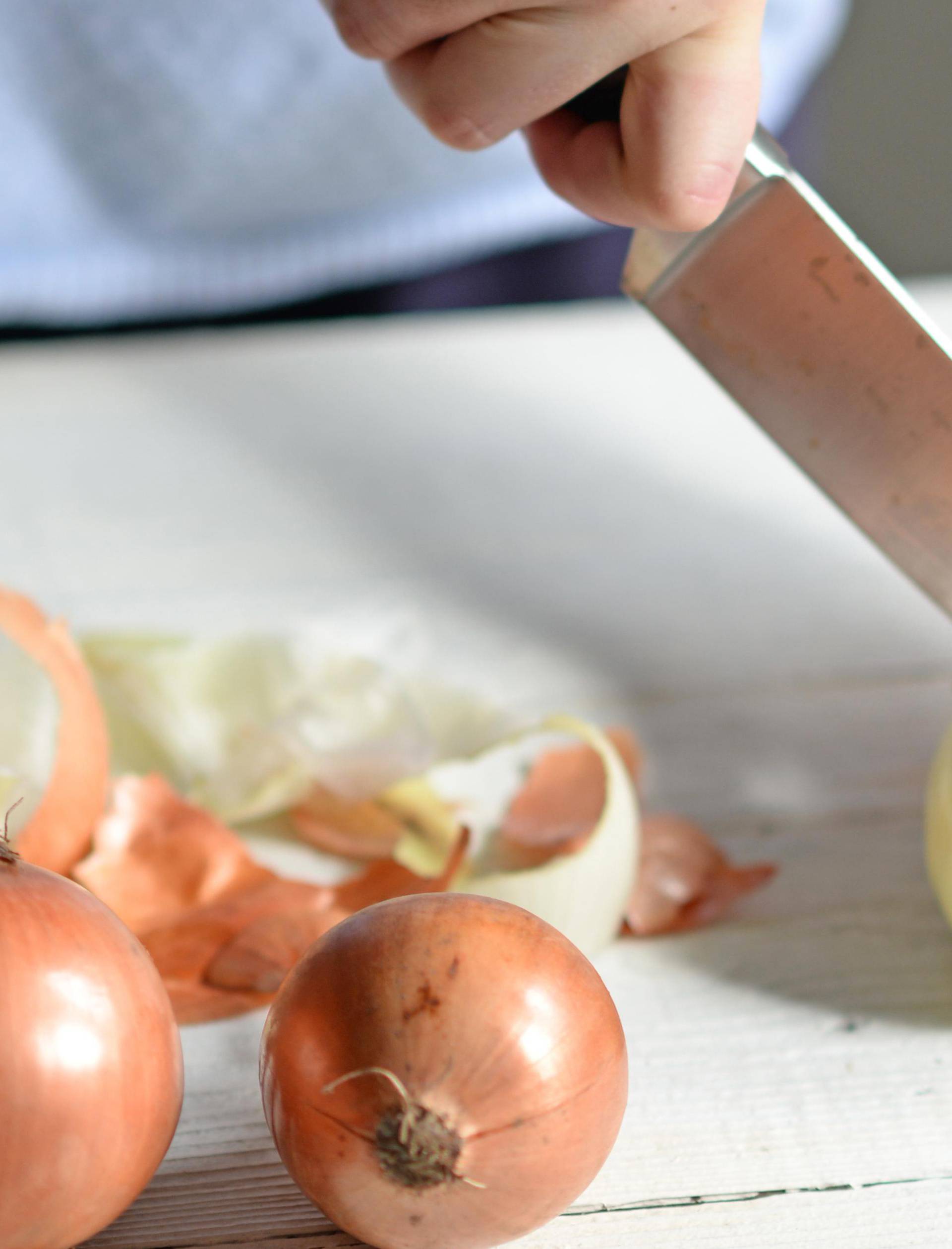 Woman hand cut fresh onion on white table