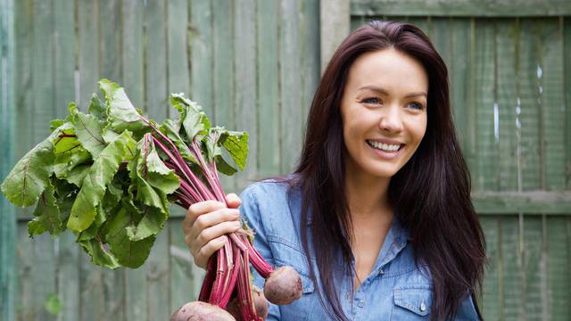 Smiling vegetarian woman holding bunch of beetroots