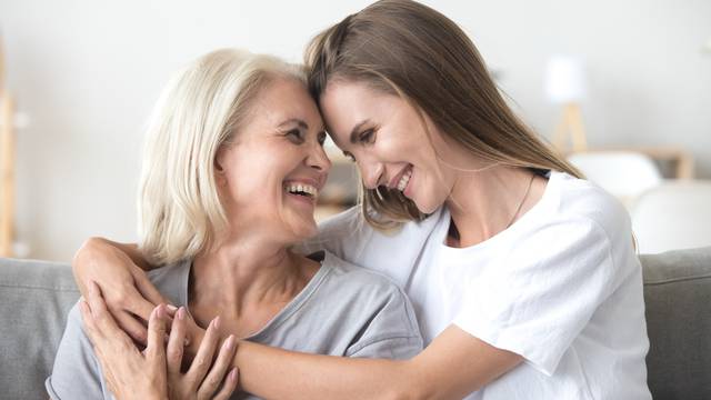 Happy loving older mother and grown millennial daughter laughing embracing