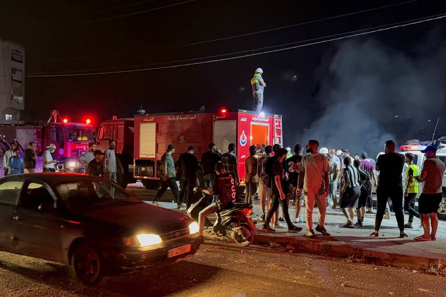 People and civil defence members gather near the site of an Israeli strike, which struck after Israel issued an evacuation warning, in Toul,