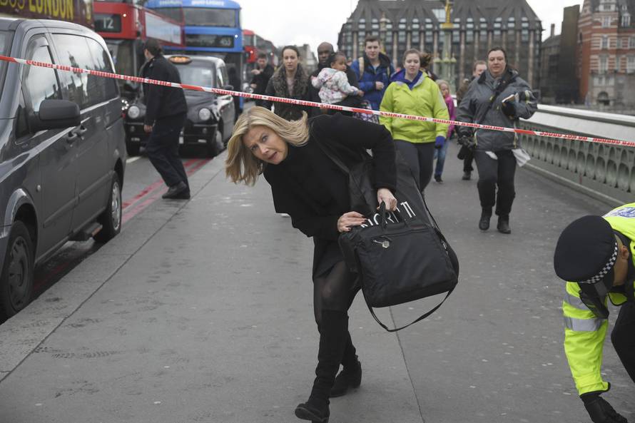 A woman ducks under a police tape after an incident on Westminster Bridge in London