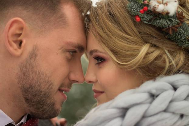 the couple is hugging and close to the kiss, holding hands, a bouquet in their hands. A suit with a butterfly and a coat with a dress. The bride and the groom
