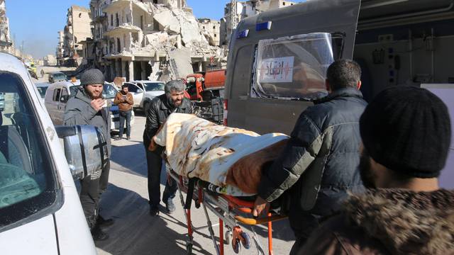 Men push an evacuee on a stretcher as vehicles wait to evacuate people from a rebel-held sector of eastern Aleppo