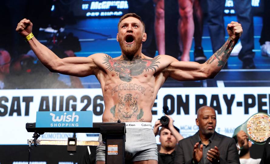 UFC lightweight champion Conor McGregor of Ireland poses on the scale during his official weigh-in at T-Mobile Arena in Las Vegas