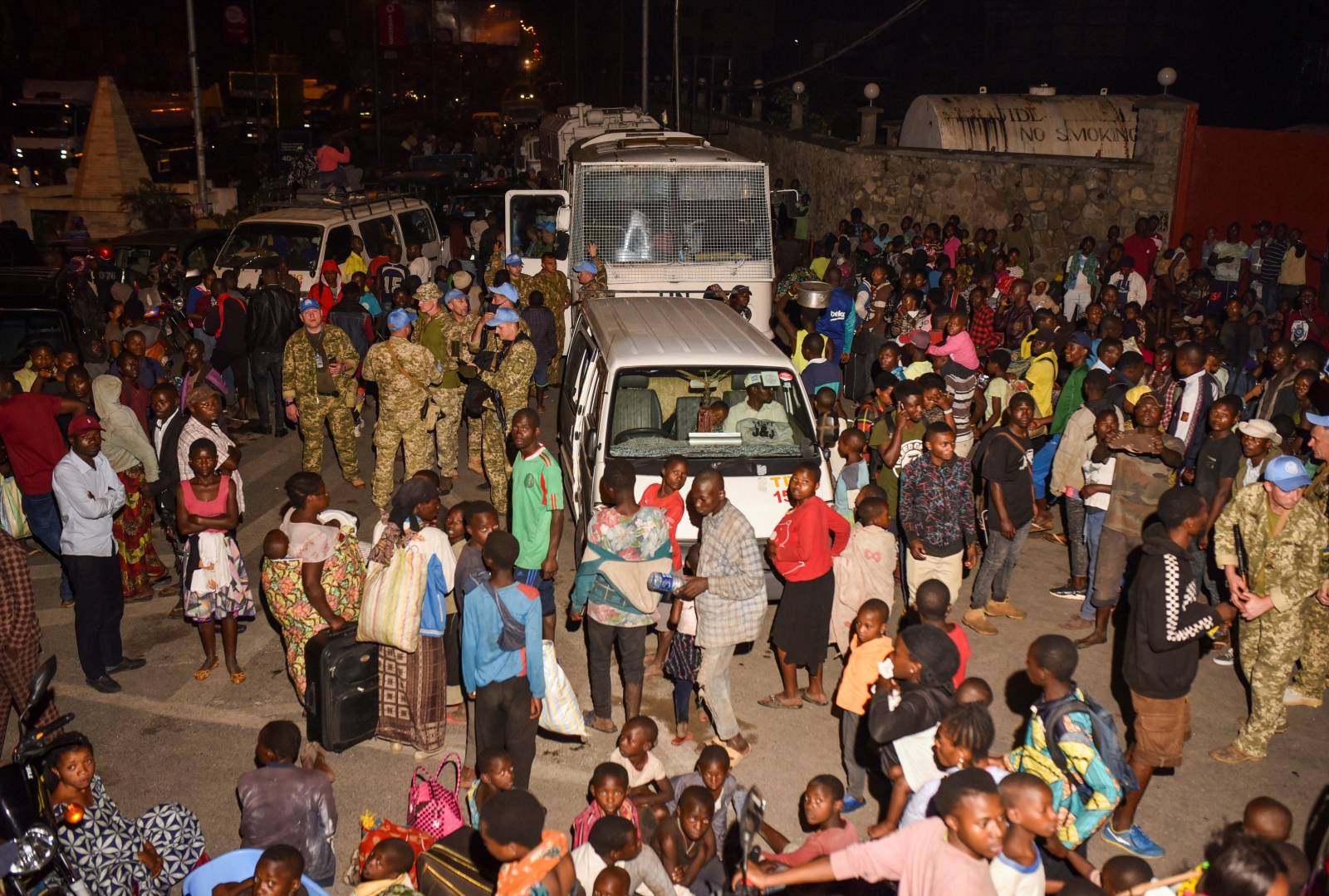 Civilians watch smoke and flames as they gather with their belongings following a volcanic activities at Mount Nyiragongo near Goma