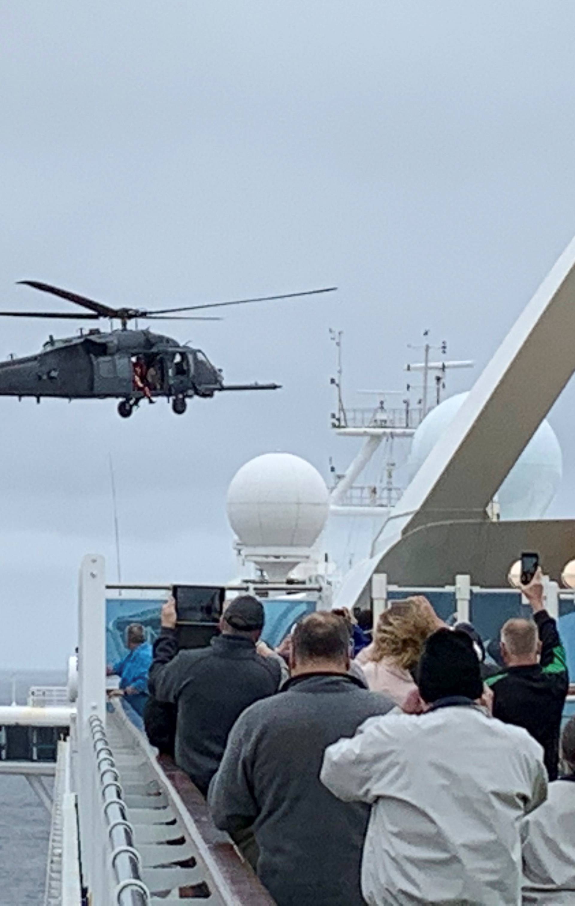 Passengers on board the Grand Princess cruise ship off San Francisco watch while a U.S. military helicopter hovers above the deck