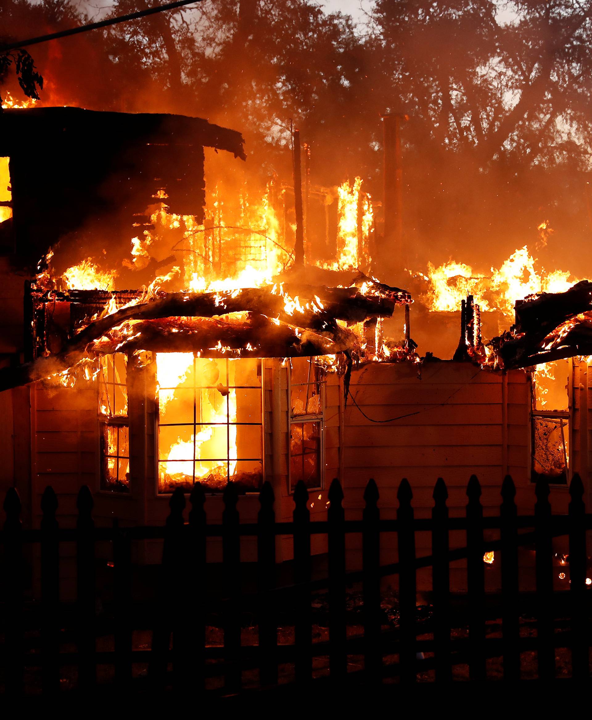 A burning house damaged by the Clayton Fire is seen near Lower Lake in California