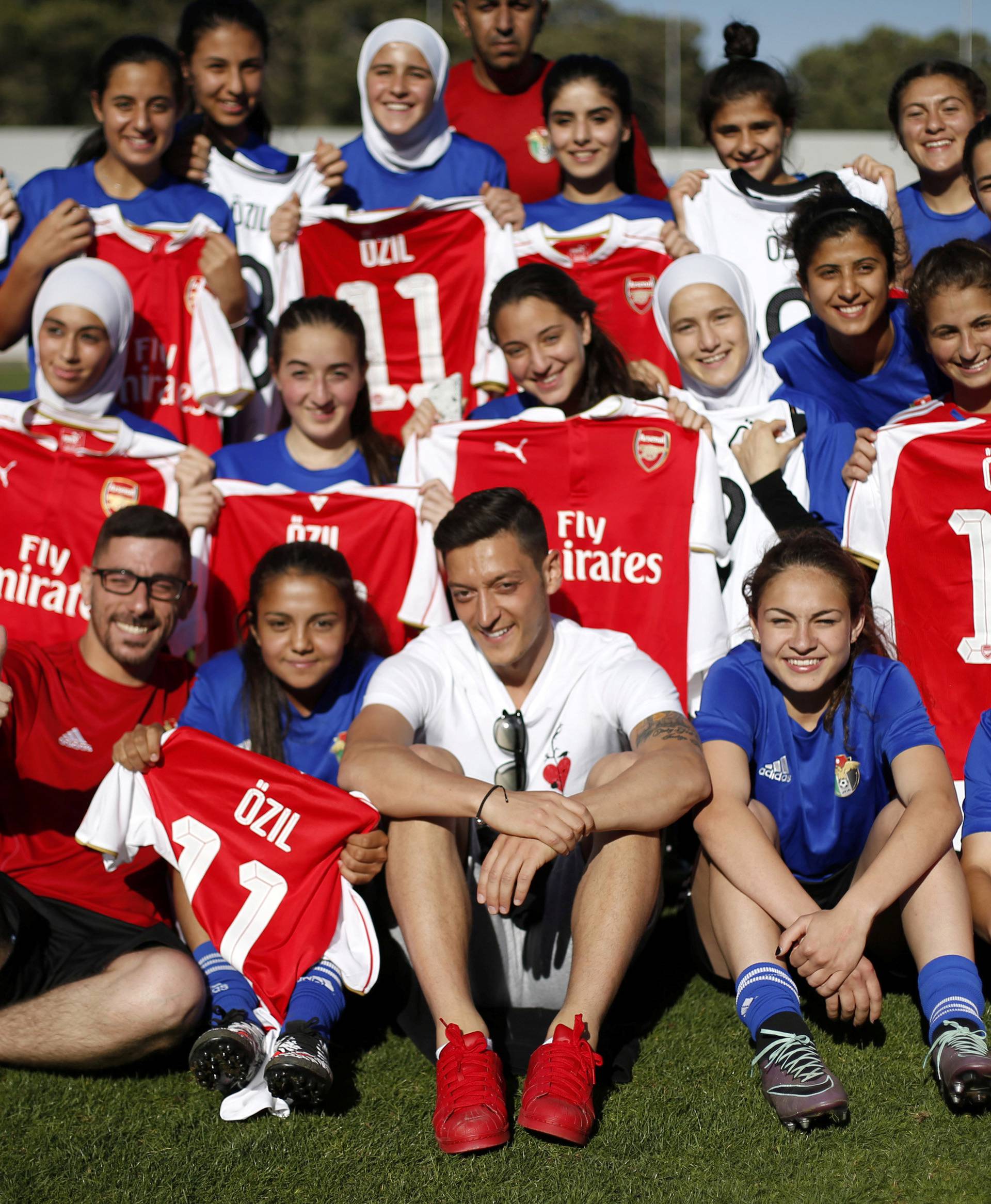 Germany and Arsenal player Mesut Ozil poses with the Jordanian U-17 women's national soccer team, after he distributed to them shirts Arsenal team as he attends the team training at Amman International Stadium in Amman