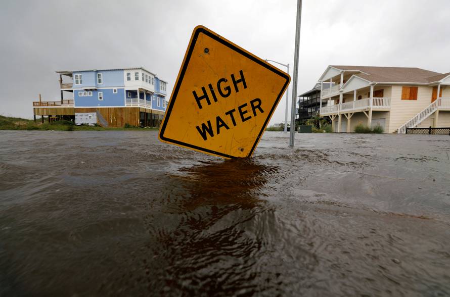 Flood waters lap at a high water warning sign that was partially pushed over by Hurricane Florence on Oak Island, North Carolina
