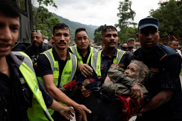 Police officers carry a survivor to a safer place following a flash flood at Trishuli, Nepal