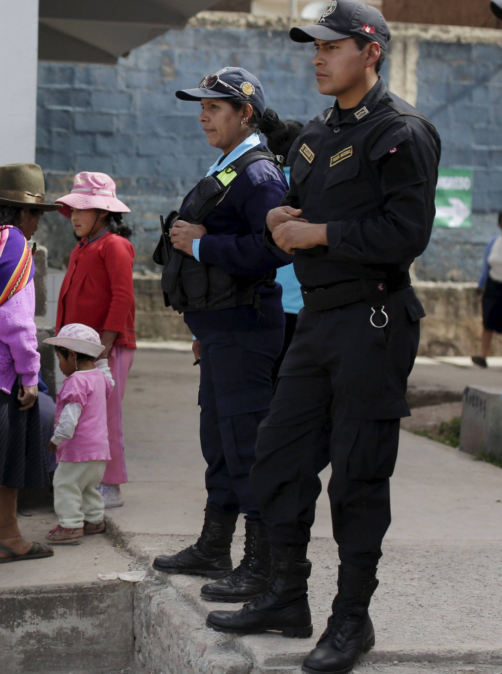 A woman walks near police officers during presidential election at a polling station in Cuzco