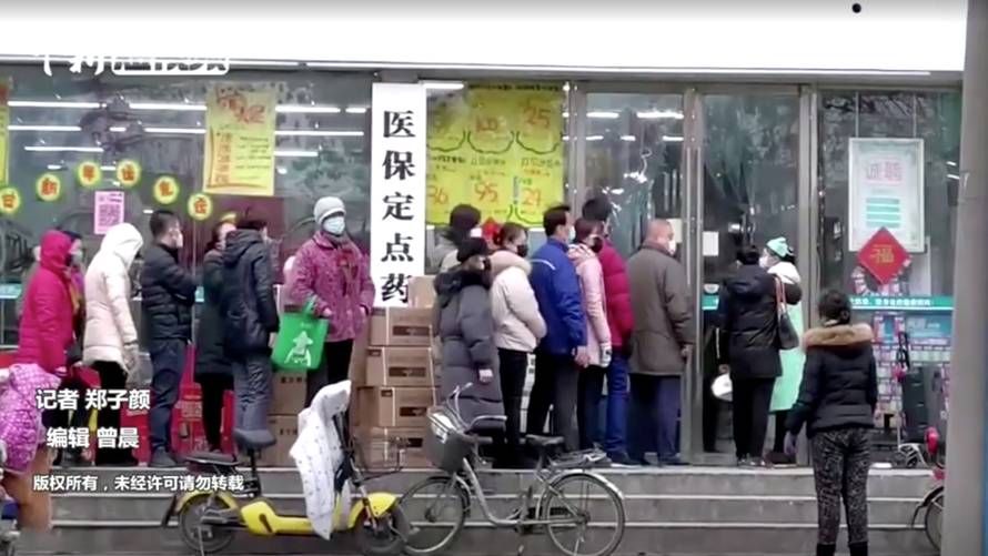 FILE PHOTO: People wearing masks queue at a shop in Wuhan