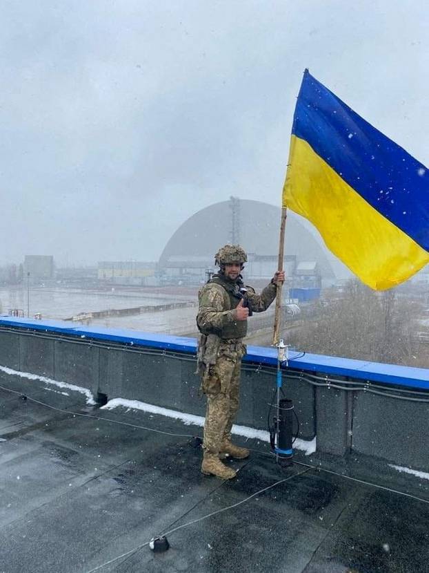 Ukrainian service member installs the Ukrainian national flag at a compound of the Chernobyl Nuclear Power Plant