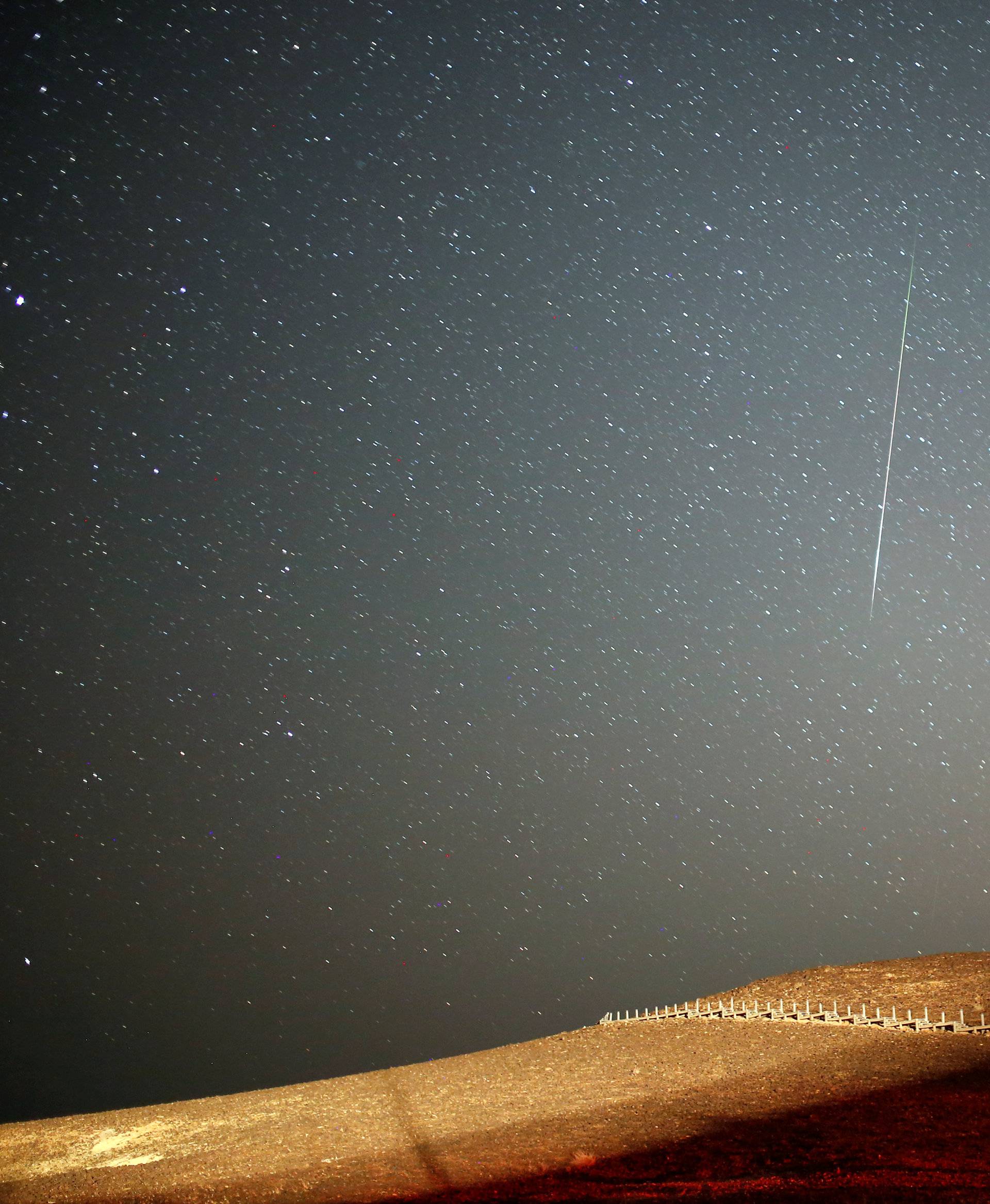 A meteor streaks across the sky in the early morning during the Perseid meteor shower in Ramon Crater near the town of Mitzpe Ramon