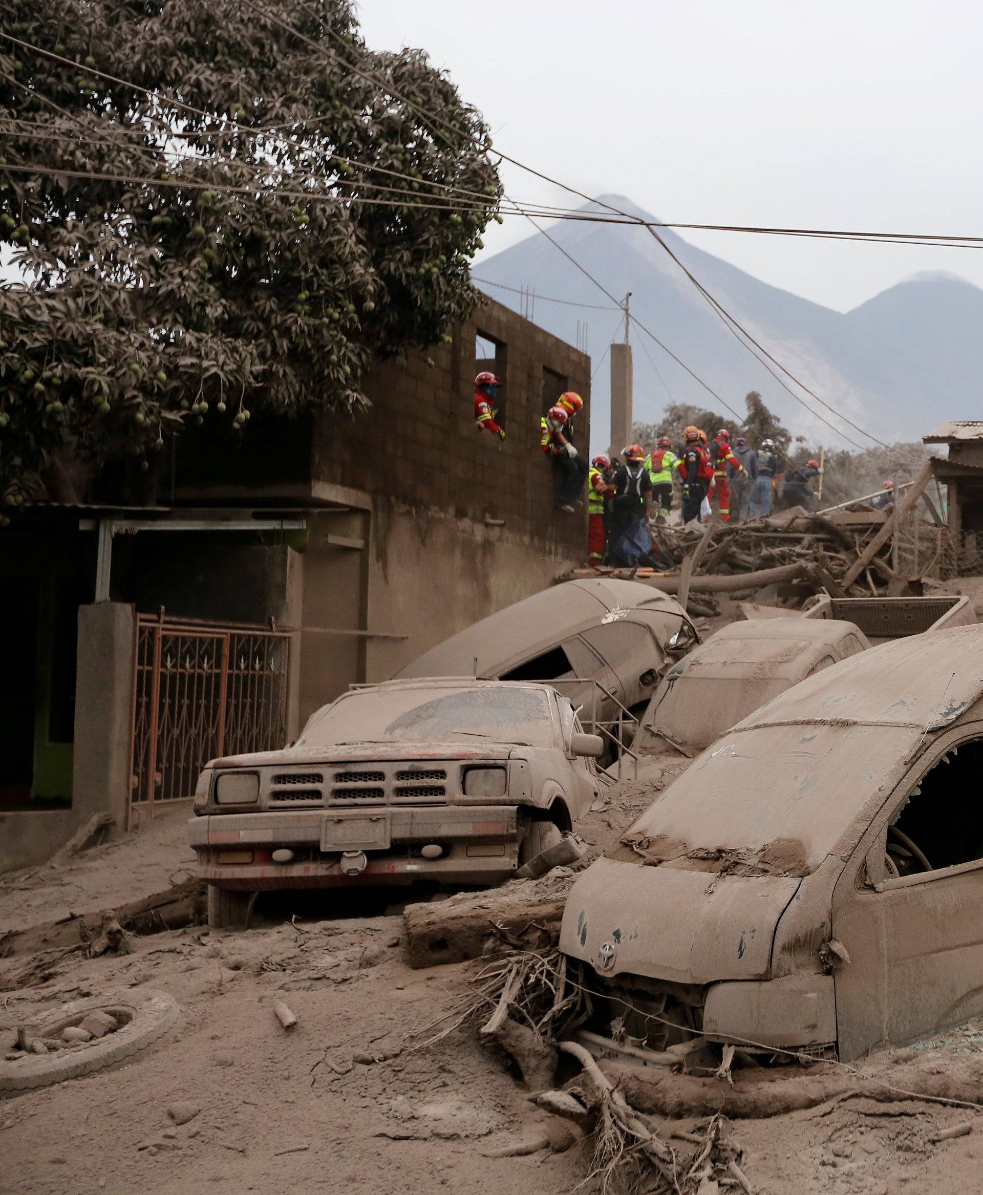 Firefighters and rescue workers look for bodies and survivors at an area affected by the eruption of the Fuego volcano in the community of San Miguel Los Lotes in Escuintla