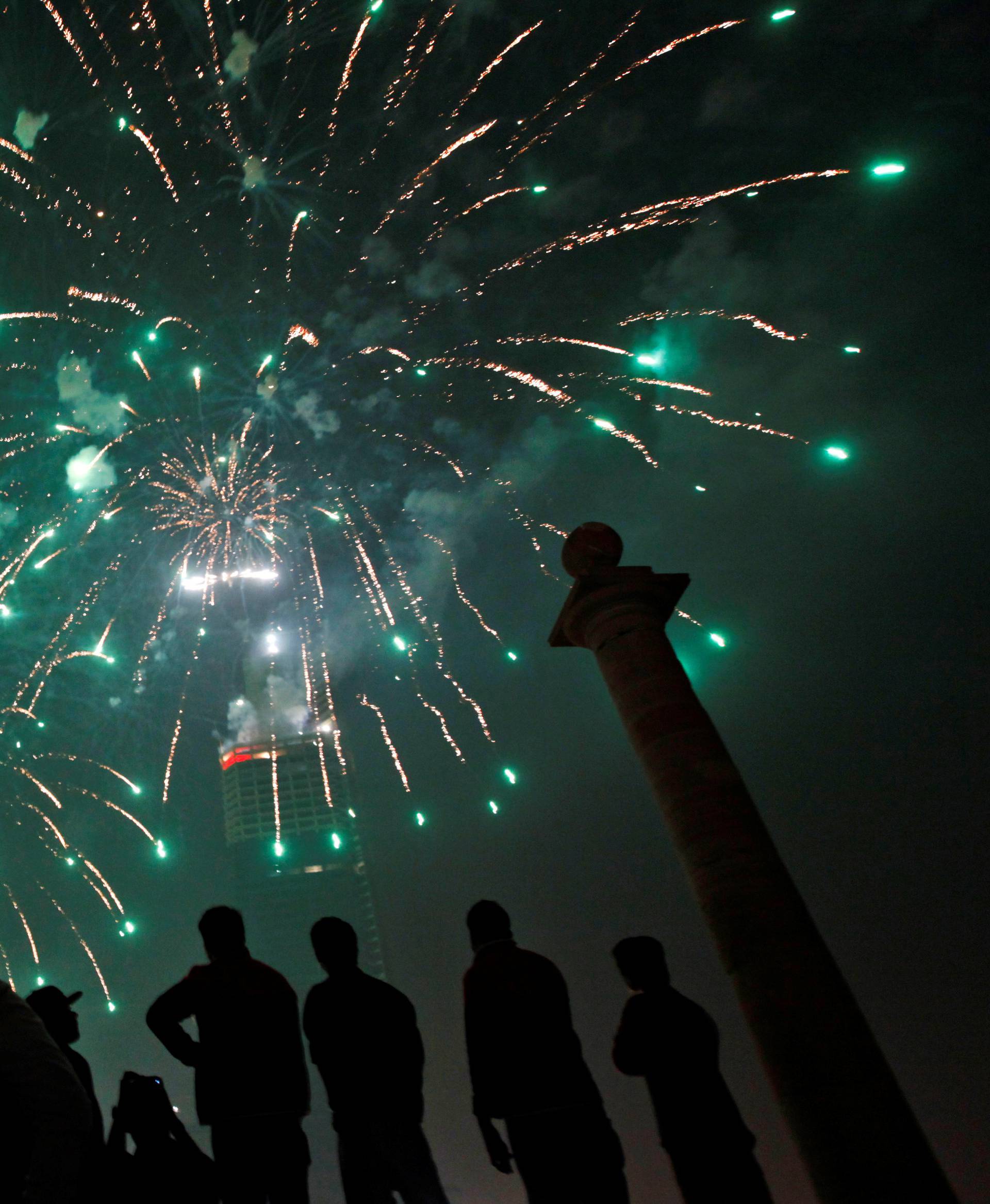 People gather to observe fireworks in celebration of the New Year in Karachi
