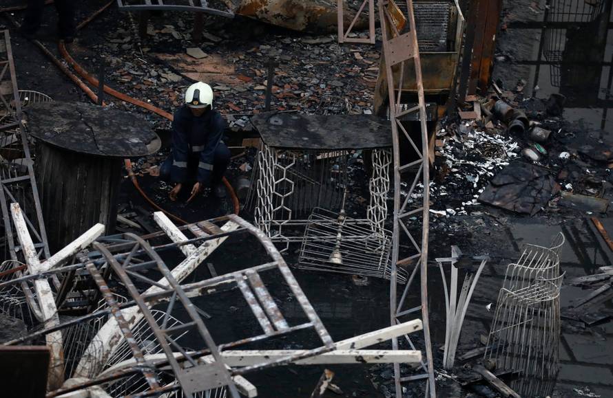A fire fighter rests amidst debris at a restaurant destroyed in a fire in Mumbai